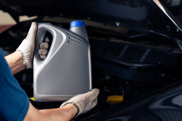 Car lubricant gallon or from gray bottle on engine background Oil change service