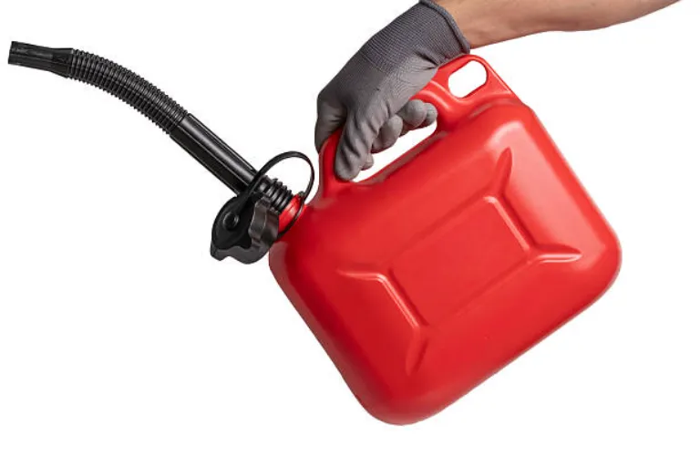 Hand in glove holding red canister of gasoline isolated on white background